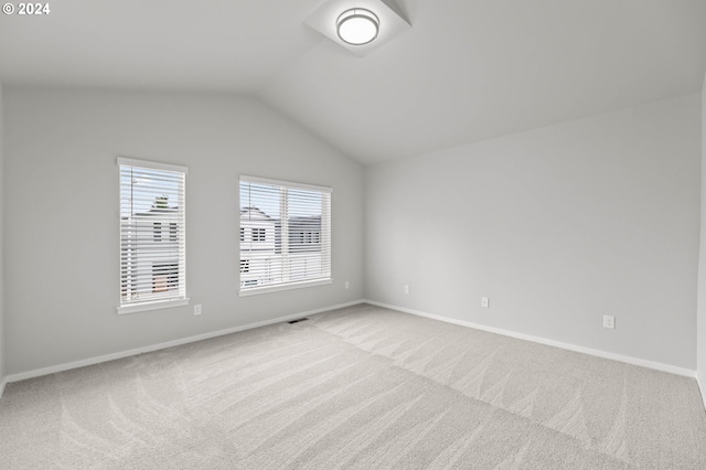 carpeted spare room with vaulted ceiling