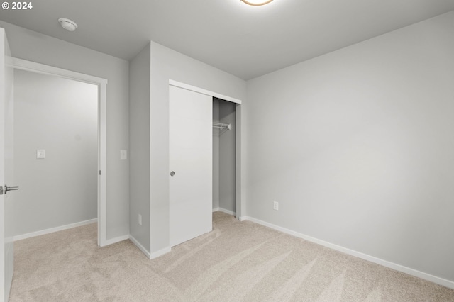 unfurnished bedroom with light colored carpet and a closet