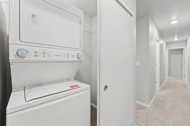 washroom featuring stacked washer / dryer and light carpet