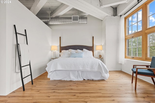 bedroom with a high ceiling, beam ceiling, and light hardwood / wood-style flooring