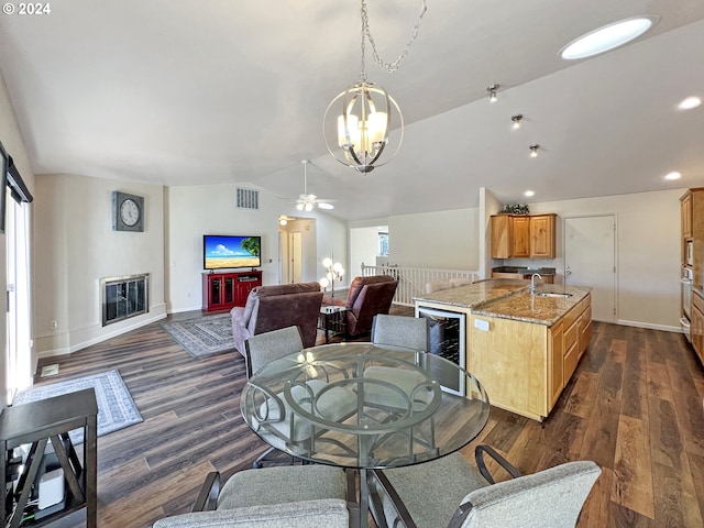 dining space featuring wine cooler, ceiling fan with notable chandelier, dark wood-type flooring, and sink