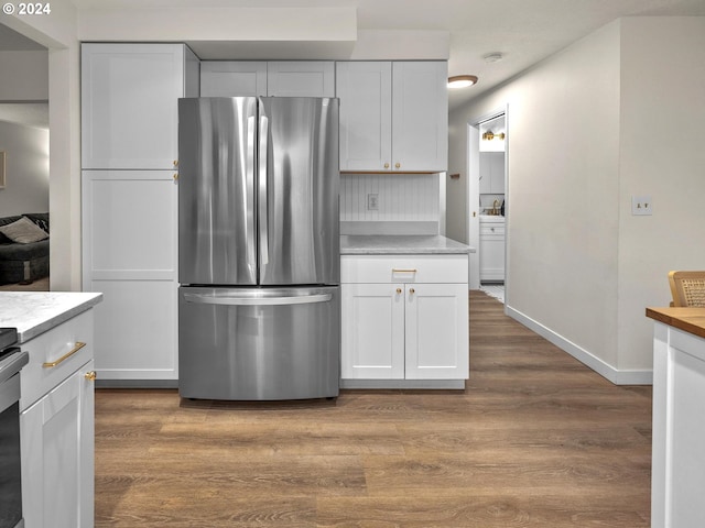 kitchen featuring stainless steel refrigerator, light hardwood / wood-style flooring, and white cabinetry