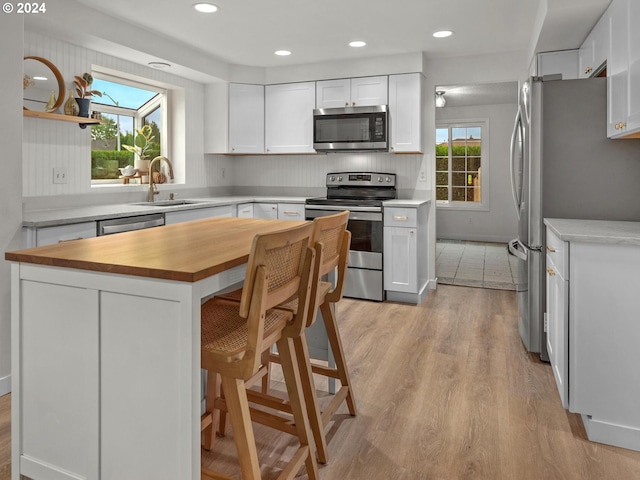 kitchen featuring sink, white cabinetry, appliances with stainless steel finishes, a breakfast bar area, and light hardwood / wood-style floors