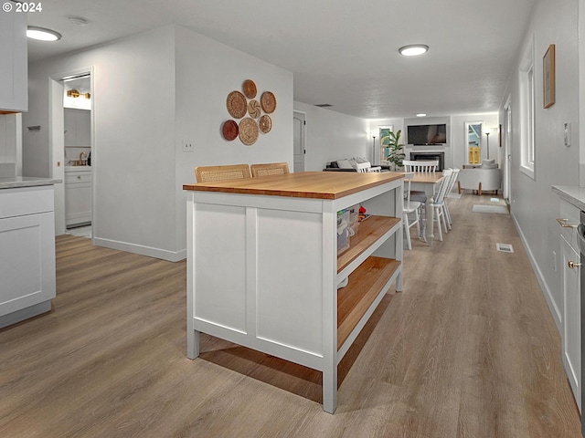 kitchen featuring light hardwood / wood-style flooring, white cabinets, a center island, and wooden counters