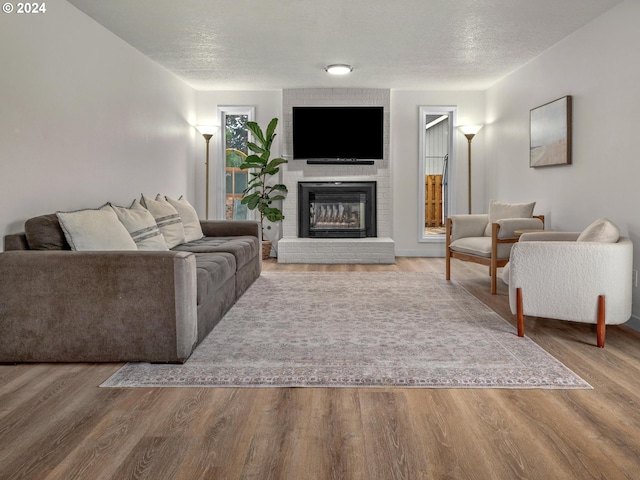 living room with a textured ceiling, wood-type flooring, and a fireplace