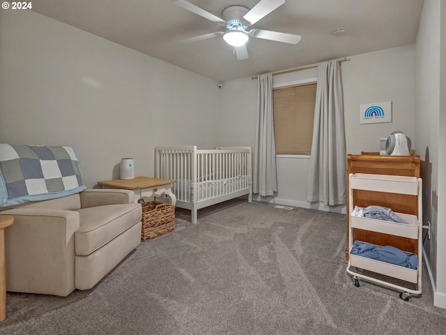 carpeted bedroom with ceiling fan and a crib