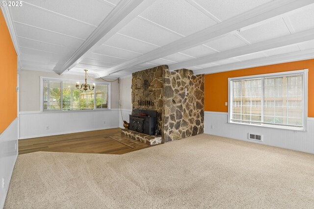 5213 Hilltop Dr, Florence, OR 97439 - unfurnished living room featuring a wood stove, wainscoting, beamed ceiling, a chandelier, and carpet
