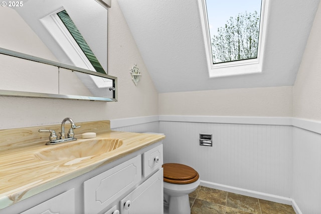5213 Hilltop Dr, Florence, OR 97439 - half bath featuring a skylight, toilet, vanity, wainscoting, and lofted ceiling