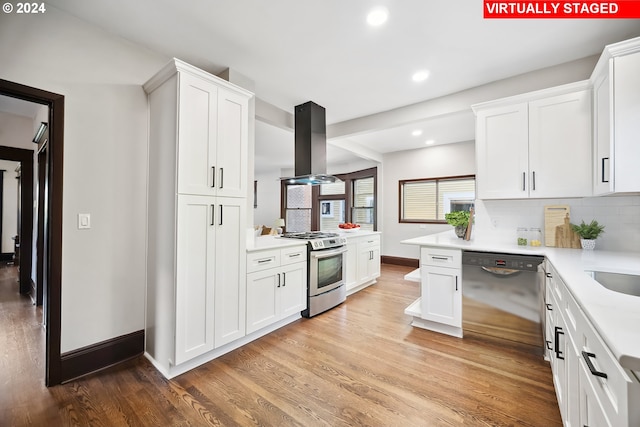 kitchen with appliances with stainless steel finishes, island exhaust hood, light wood-type flooring, and white cabinets