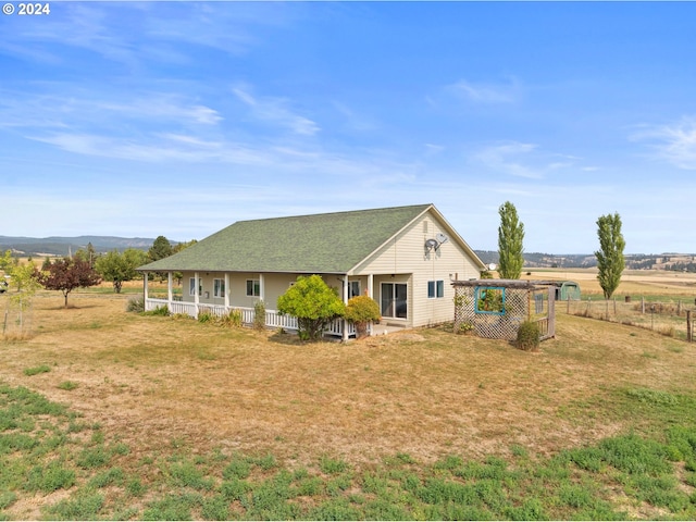 back of property with a mountain view, a rural view, and a lawn