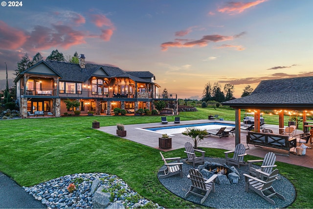 yard at dusk featuring a patio area, a balcony, and an outdoor fire pit