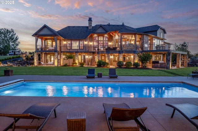 rear view of property with a balcony, a patio area, and a lawn