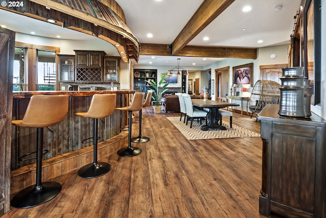 bar featuring tasteful backsplash, hanging light fixtures, hardwood / wood-style flooring, beam ceiling, and dark brown cabinetry