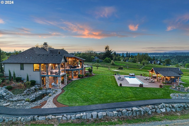 back house at dusk featuring a lawn, a patio area, and a gazebo