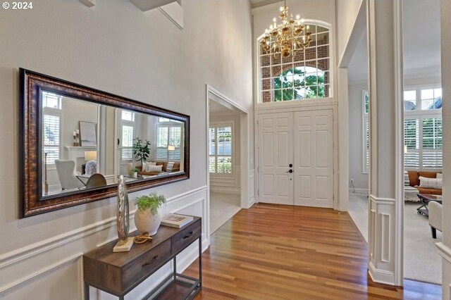 foyer entrance with light carpet, a towering ceiling, and an inviting chandelier