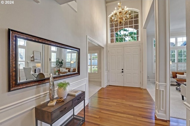 entryway featuring hardwood / wood-style flooring, a healthy amount of sunlight, a chandelier, and a high ceiling