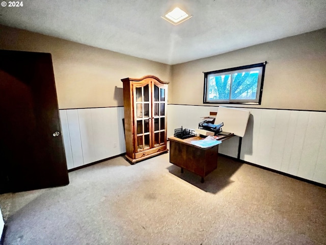 office with a textured ceiling, wood walls, and light carpet