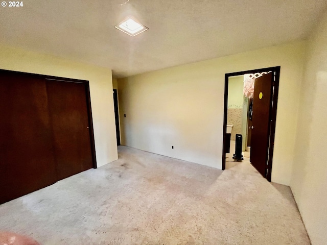 unfurnished bedroom with light carpet and a closet