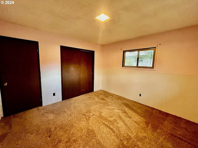 unfurnished bedroom featuring carpet, a textured ceiling, and a closet