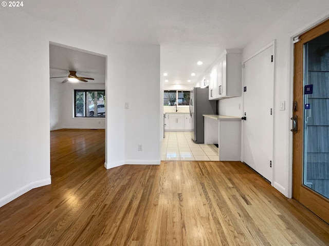 interior space with stainless steel fridge, light hardwood / wood-style floors, white cabinetry, and sink