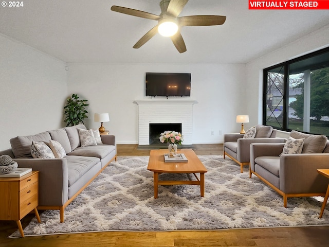 living room with hardwood / wood-style floors, ceiling fan, and a fireplace