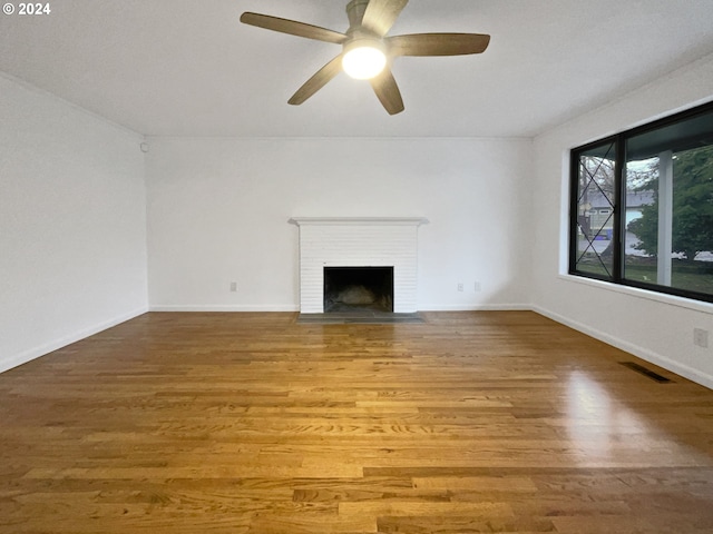 unfurnished living room with hardwood / wood-style floors, ceiling fan, and a fireplace