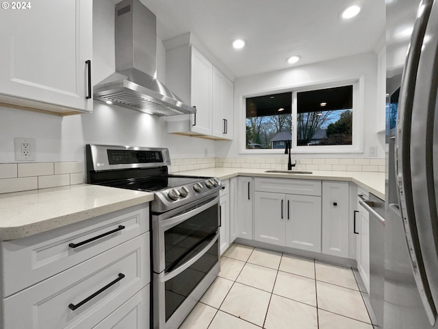 kitchen with sink, white cabinets, stainless steel appliances, and wall chimney range hood