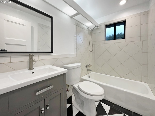 full bathroom with vanity, tiled shower / bath combo, tile walls, tile patterned flooring, and toilet