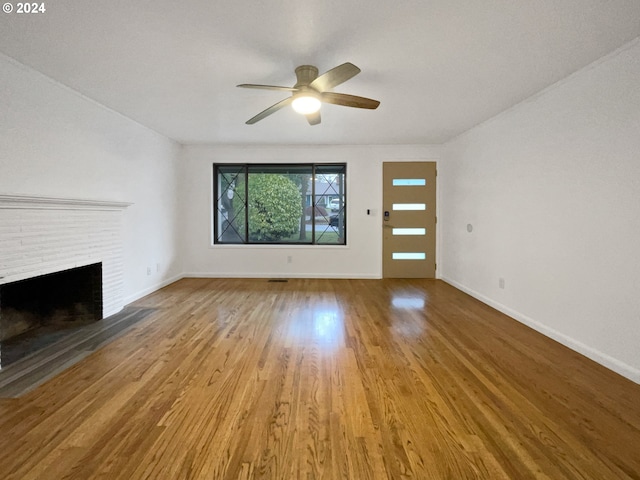 unfurnished living room featuring light hardwood / wood-style flooring, a brick fireplace, and ceiling fan