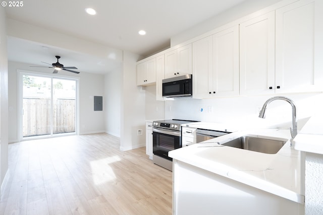 kitchen with kitchen peninsula, appliances with stainless steel finishes, light hardwood / wood-style flooring, and white cabinetry