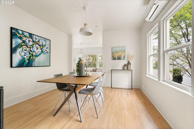 dining room featuring light hardwood / wood-style flooring, a healthy amount of sunlight, and a wall mounted AC