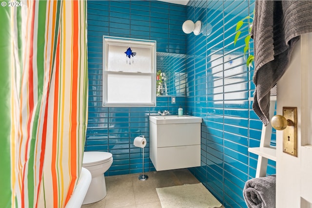 bathroom featuring toilet, curtained shower, tile patterned floors, tile walls, and vanity