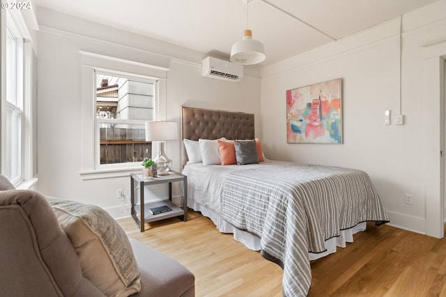 bedroom with a wall unit AC and hardwood / wood-style floors