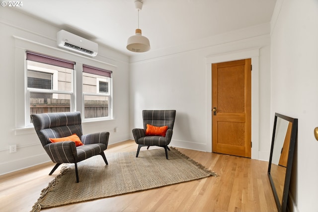 sitting room with an AC wall unit, crown molding, and light wood-type flooring