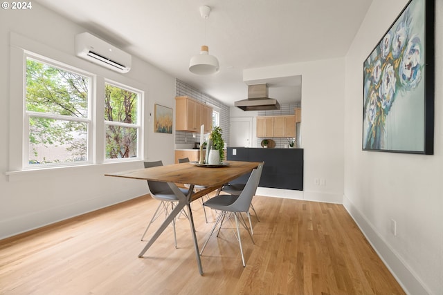 dining space featuring light wood-type flooring and a wall mounted AC