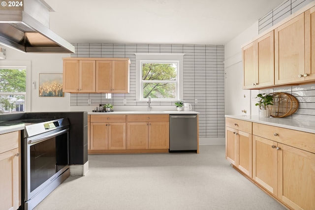 kitchen with wall chimney exhaust hood, tile walls, light brown cabinets, and stainless steel appliances