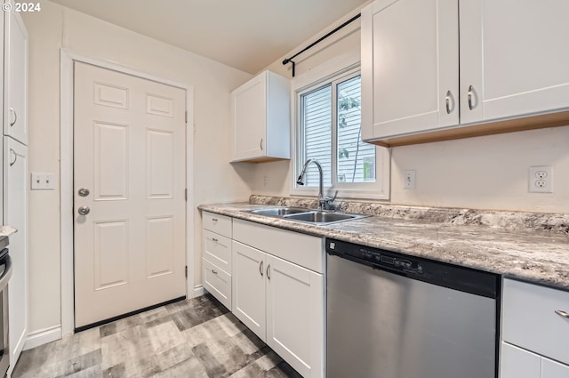 kitchen with light wood-type flooring, light stone counters, stainless steel dishwasher, white cabinets, and sink