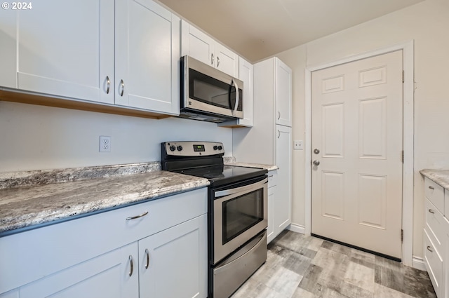 kitchen featuring light hardwood / wood-style floors, white cabinetry, stainless steel appliances, and light stone countertops