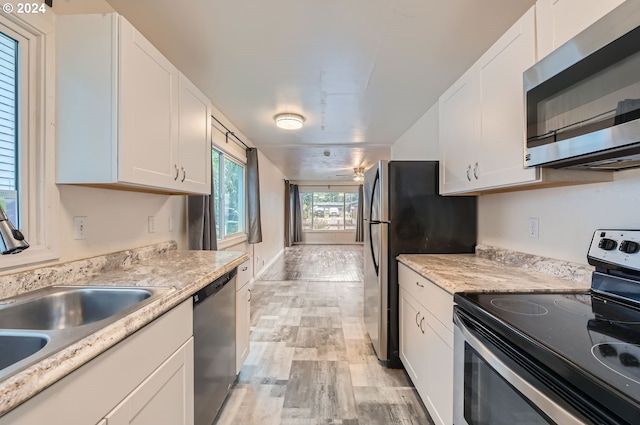 kitchen with sink, stainless steel appliances, light hardwood / wood-style floors, and white cabinetry