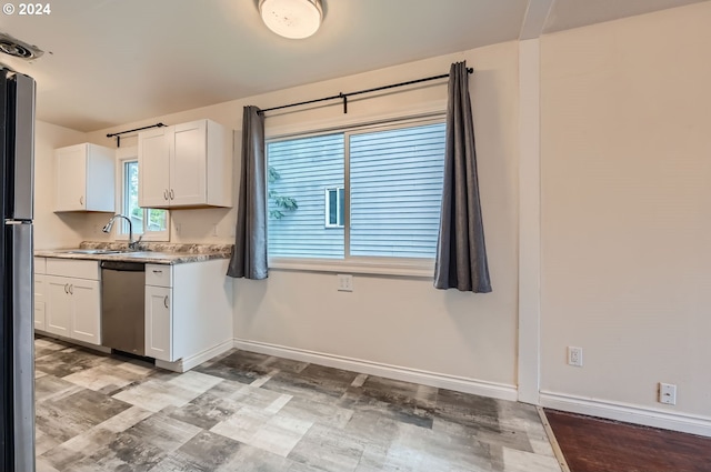 kitchen with sink, light wood-type flooring, white cabinetry, and stainless steel dishwasher