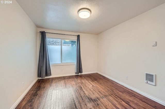 unfurnished room featuring dark wood-type flooring and heating unit