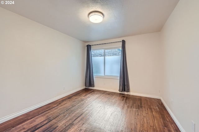 empty room with a textured ceiling and dark hardwood / wood-style floors