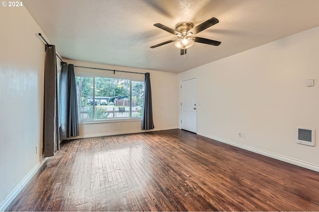 empty room featuring ceiling fan, heating unit, dark wood-type flooring, and a textured ceiling