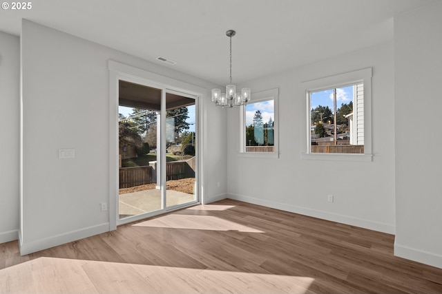 unfurnished dining area with hardwood / wood-style flooring and a notable chandelier