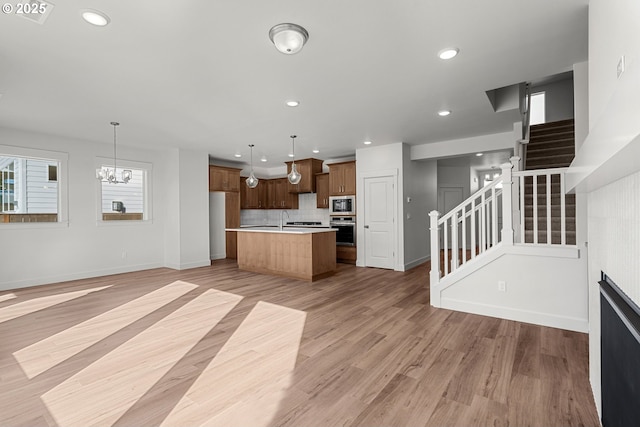 kitchen with built in microwave, a center island, pendant lighting, oven, and decorative backsplash