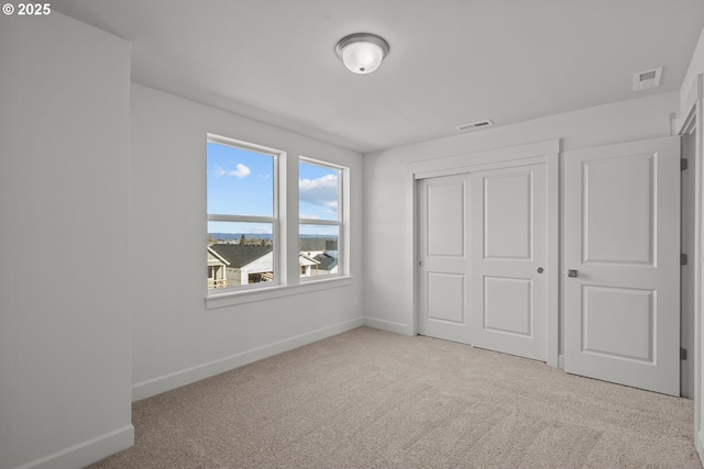 unfurnished bedroom featuring light carpet and a closet