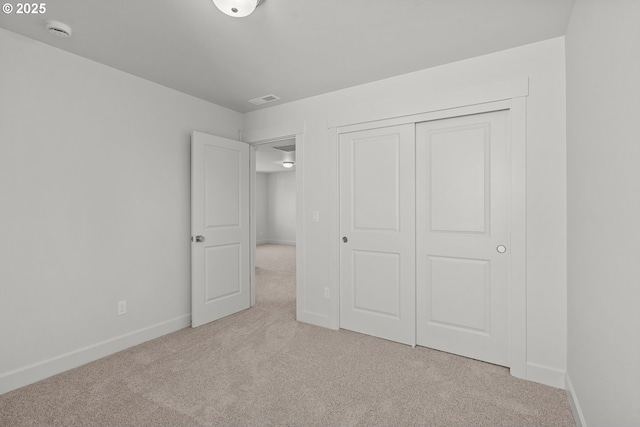 unfurnished bedroom featuring light carpet and a closet