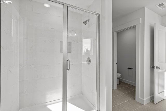 bathroom with an enclosed shower, tile patterned flooring, and toilet