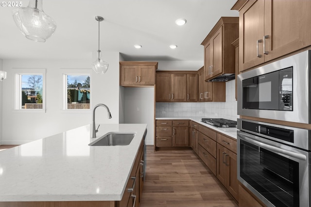 kitchen featuring sink, light stone countertops, an island with sink, stainless steel gas cooktop, and built in microwave