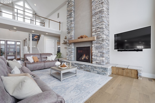 living room with a fireplace, a high ceiling, and light hardwood / wood-style flooring